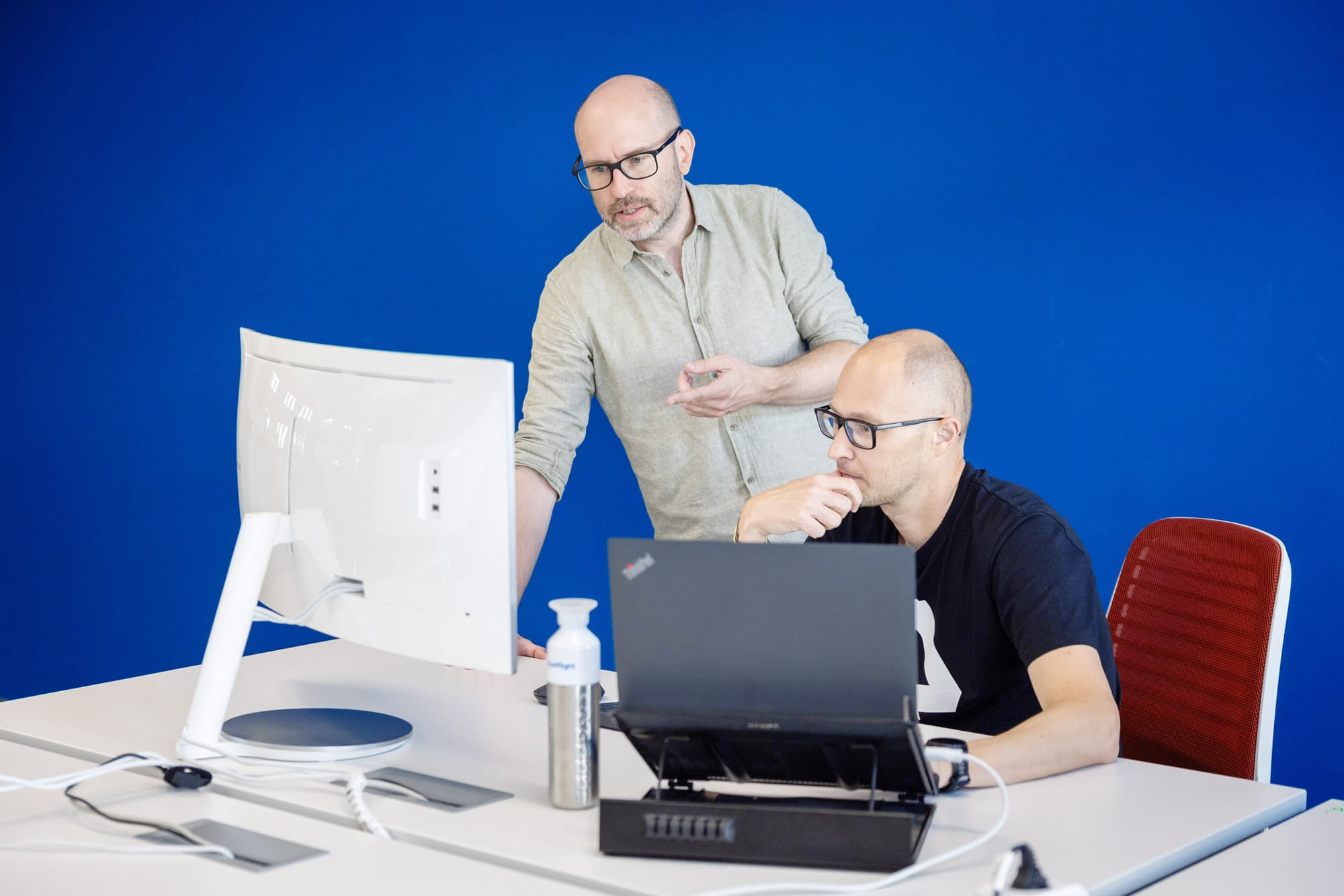 The image shows 2 engineers discussing a project on their desk.